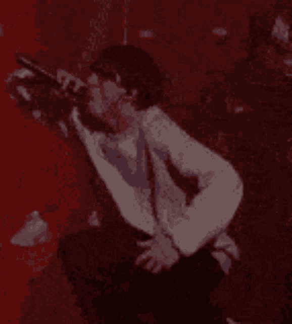 a man in a white sweater is singing into a microphone on a stage .