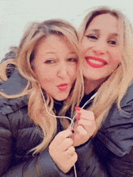 two women are posing for a picture and one is wearing earbuds