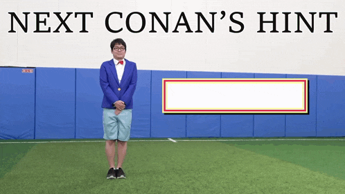 a man in a blue suit stands in front of a sign that says next conan 's hint