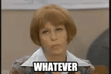 a woman in a wig is sitting in a classroom with the words `` whatever '' written on her face .