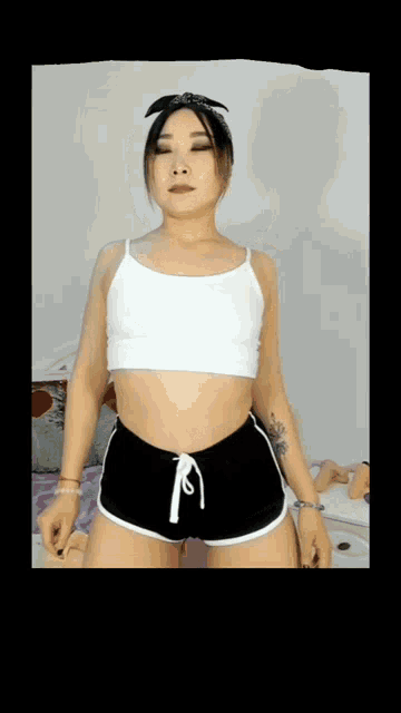 a woman in a white top and black shorts is dancing