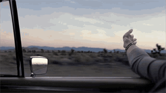 a person 's hand is sticking out of a car window and giving the middle finger