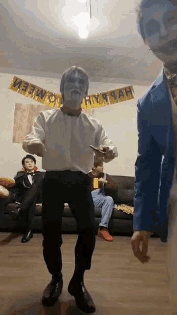 a man in a zombie costume is dancing in front of a couch with a banner that says happy new year