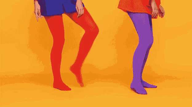 two women wearing red and purple tights are dancing together on a yellow background .
