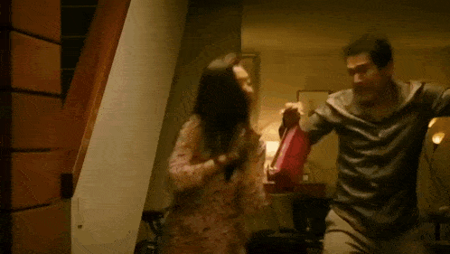 a woman in a pink dress is dancing with a man in a black shirt .