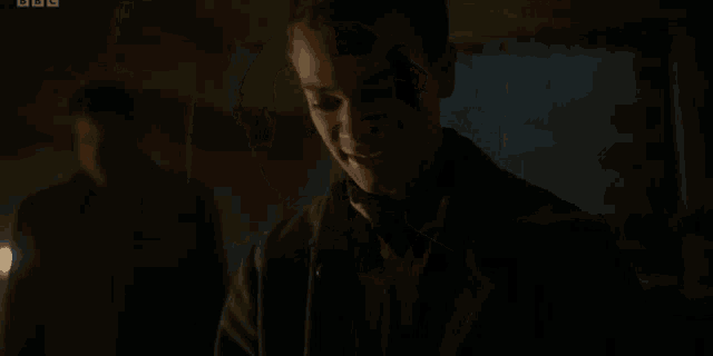 a young man is standing in a dark room with his eyes closed and looking down .