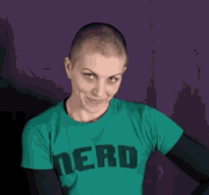 a woman with a shaved head is wearing a green nerd t-shirt and making a funny face .