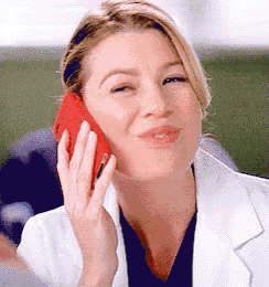 a woman in a white lab coat is talking on a red cell phone