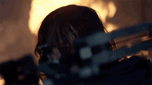 a woman is holding a chainsaw in front of a fire in a dark room .