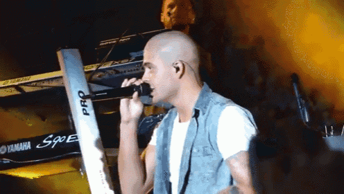a man singing into a microphone in front of a keyboard that says pro