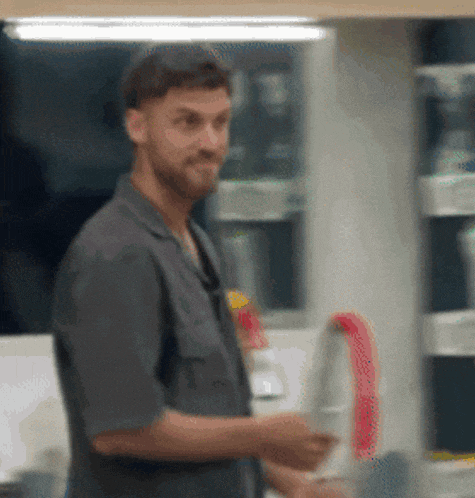 a man with a beard is standing in a kitchen holding a knife
