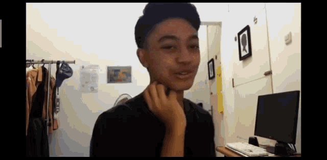 a young man is sitting in front of a computer in a bedroom .