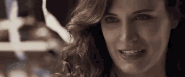 a close up of a woman 's face with a hat on smiling .