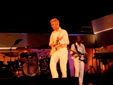 a man in white playing a guitar on stage