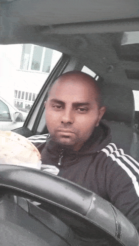 a man sitting in a car holding a tortilla