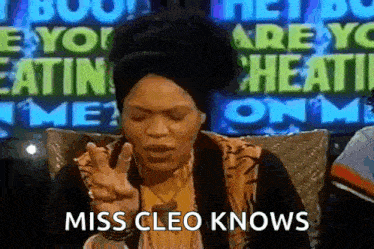 a woman is sitting in front of a sign that says ' miss cleo knows '