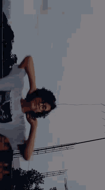 a person with curly hair is wearing glasses and a white shirt