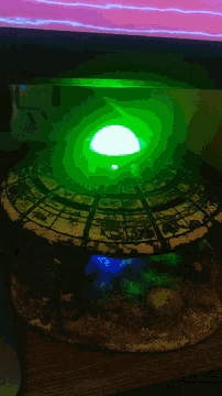 a green light is shining on a statue of a planet