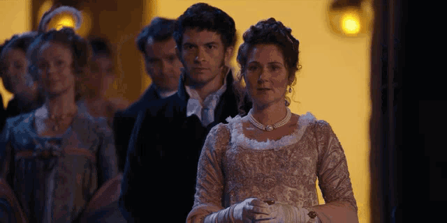 a woman in a white dress stands in front of a group of people