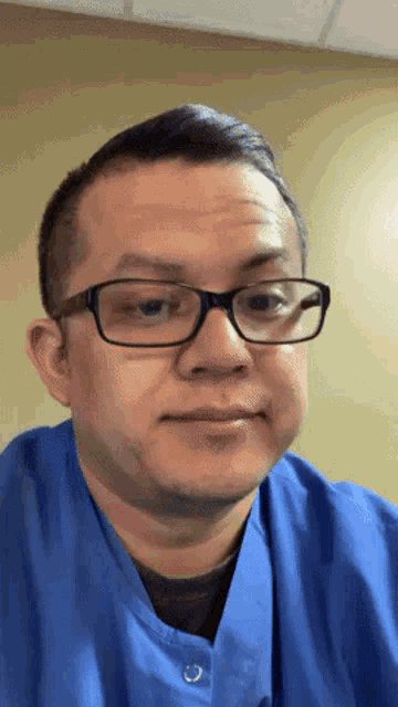 a man wearing glasses and a blue scrub shirt