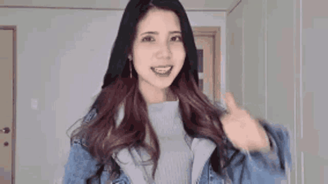 a woman with long hair is wearing a denim jacket and a sweater .