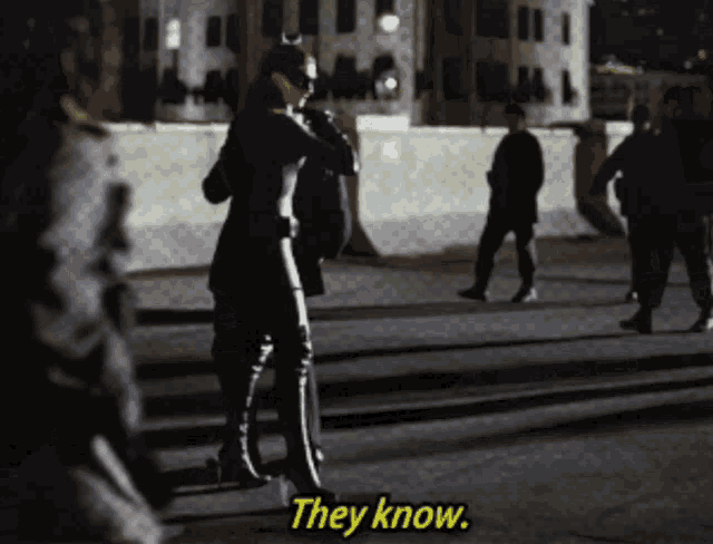 a woman in a catwoman costume is walking down a street and says they know