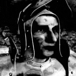 a black and white photo of a man wearing a knight 's helmet .
