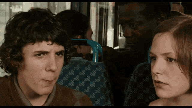 a man and a girl are sitting on a bus and the girl is looking at the man