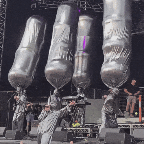 a group of people standing on a stage with silver balloons hanging from the ceiling