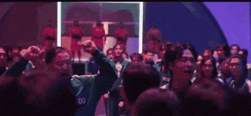 a crowd of people with their arms in the air and a man wearing a number o shirt
