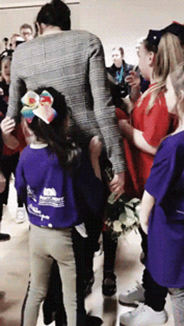 a girl in a purple shirt with a rainbow bow is standing next to a woman