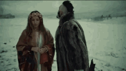 a man and a woman are standing in the snow on a beach .