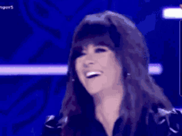 a woman with long hair is smiling in front of a blue background .