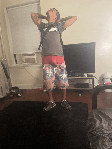 a man standing in front of a flat screen tv with his hands behind his head