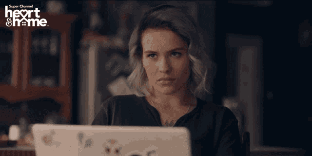 a woman is sitting at a table with a laptop and the words heart & home on the bottom