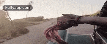 a person is sitting in a car with their hands out the window .