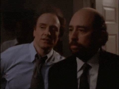 two men are standing next to each other in a dark room .