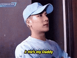 a man wearing a hat and a blue shirt is talking to someone .