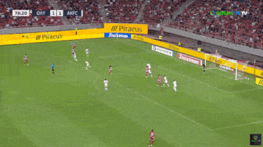 a soccer game is being played in a stadium with piraeus advertisements on the sidelines