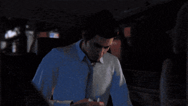 a man in a blue shirt and tie is looking out of a car window