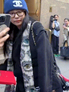 a woman wearing a blue hat with the letter j on it is taking a picture of herself with her phone .