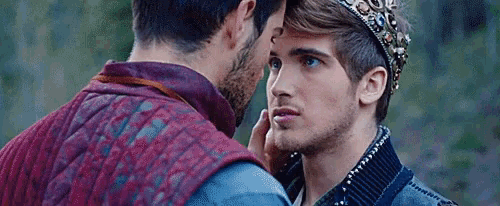 a man with a crown on his head is touching the face of another man .