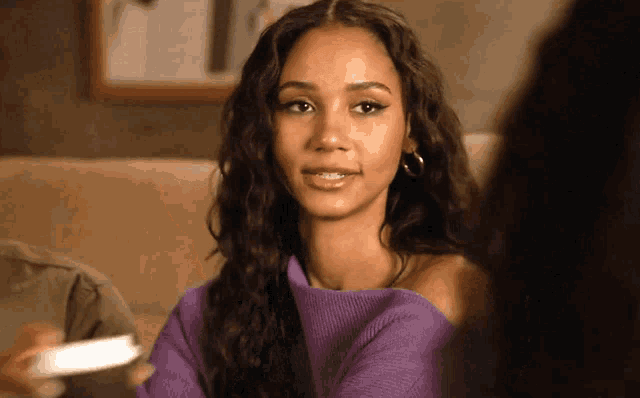 a woman wearing a purple sweater and hoop earrings