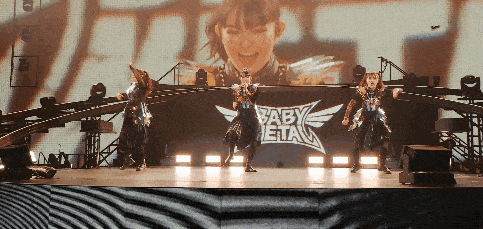 a group of girls are dancing on a stage in front of a babymetal logo