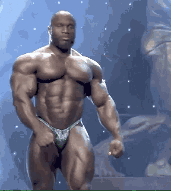 a bodybuilder in a green bikini is standing on a stage