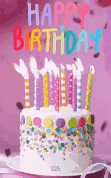 a birthday cake with candles and sprinkles on a plate on a table .