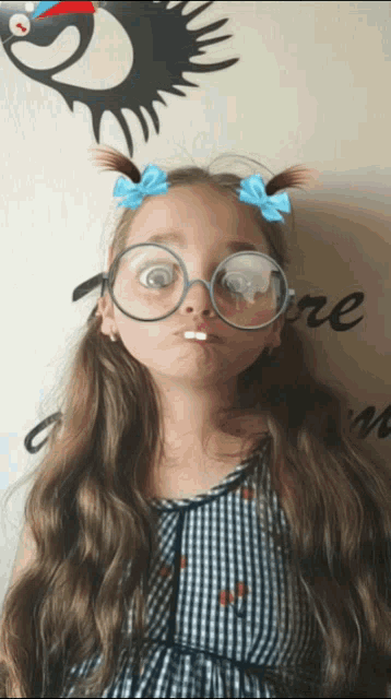 a little girl wearing glasses and pigtails makes a face