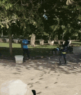a man in a batman costume is walking down a sidewalk in a park