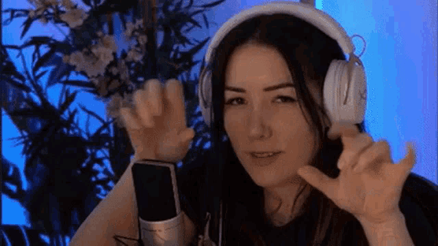 a woman wearing headphones is sitting in front of a microphone and making a funny face .