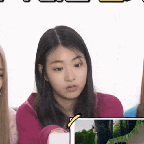a girl in a pink shirt is looking at a picture of a forest